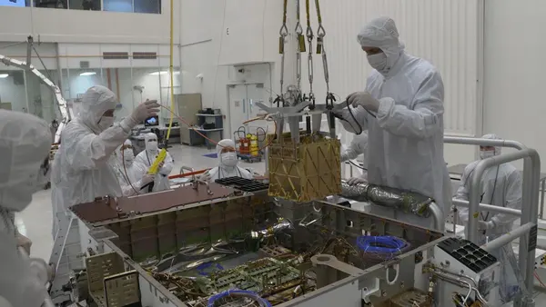 Engineers lower the MOXIE instrument into the chassis of NASA's Perseverance rover